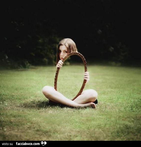 Ragazza con specchio sul prato. Illusione ottica dell'invisibilità