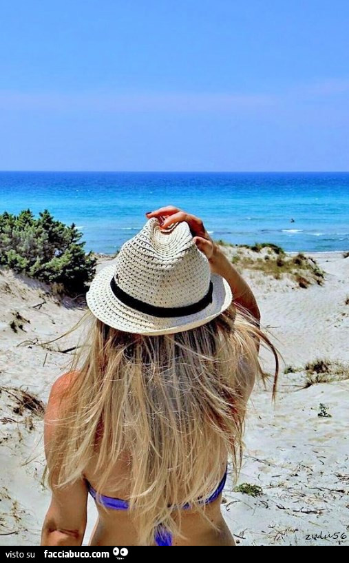 Ragazza bionda al mare con cappello in testa
