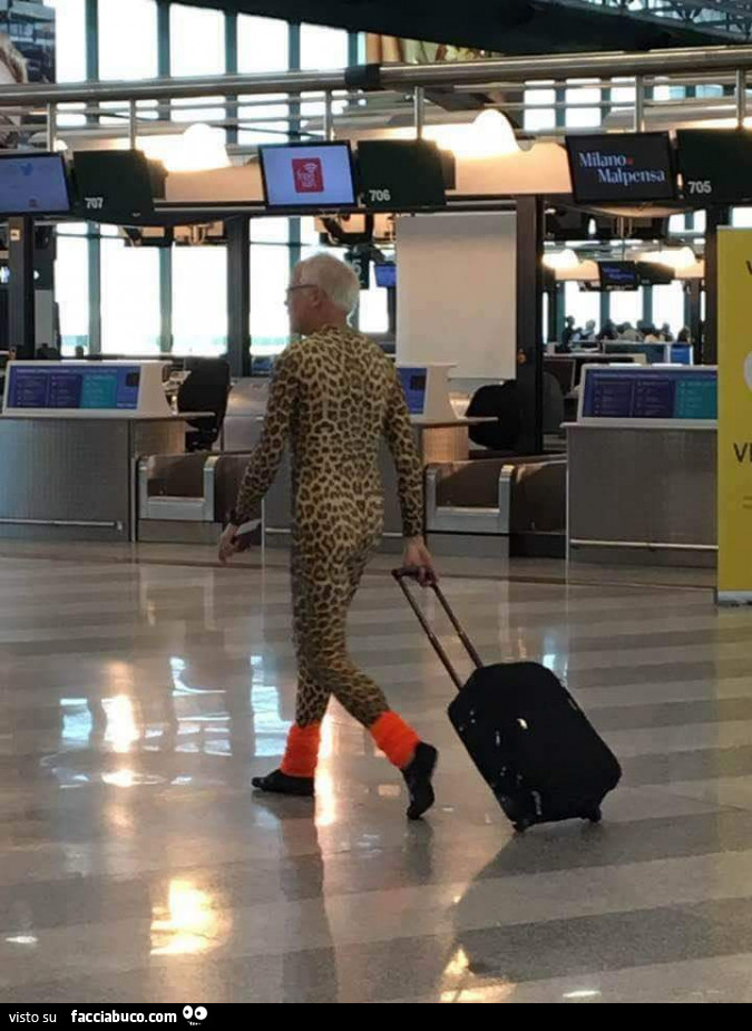 Uomo in tutina leopardata all'aereoporto con il trolley